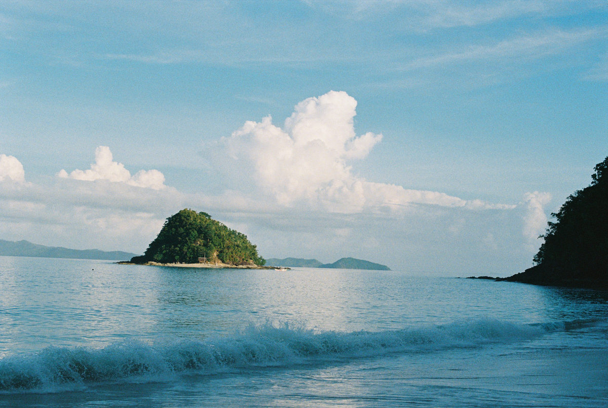 Small green island beyond a breaking wave