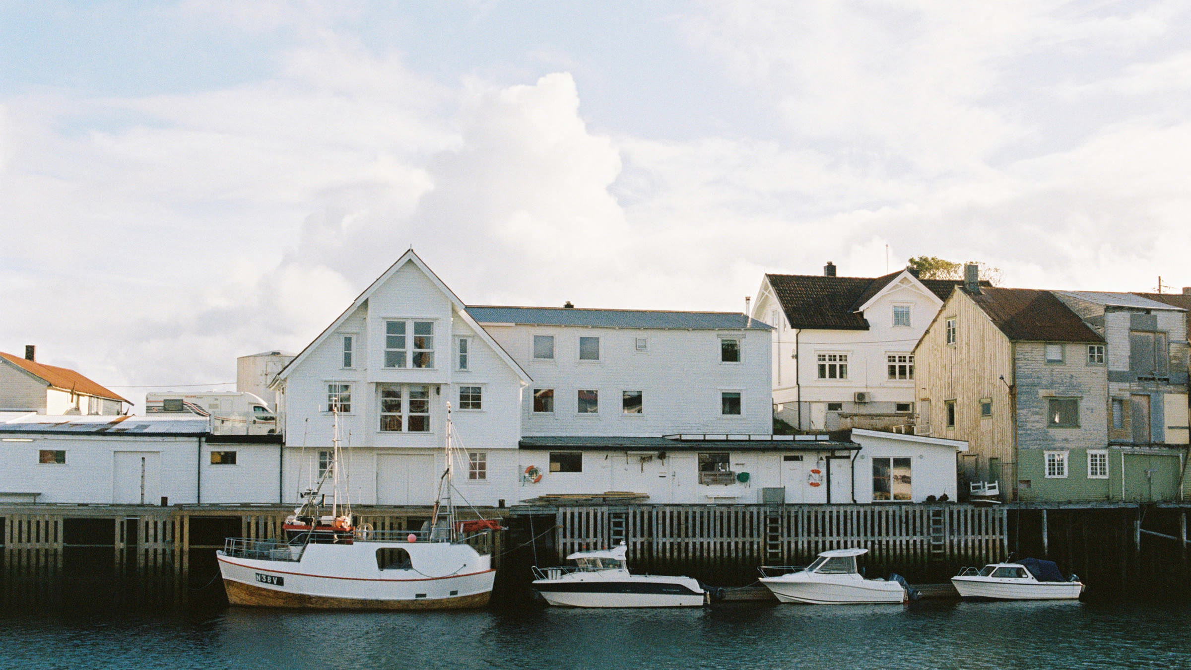 White wooden houses and fishing boats along a harbour in Norway