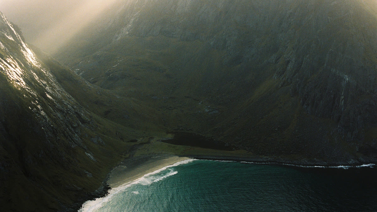 Rays of light falling into a steep green fjord